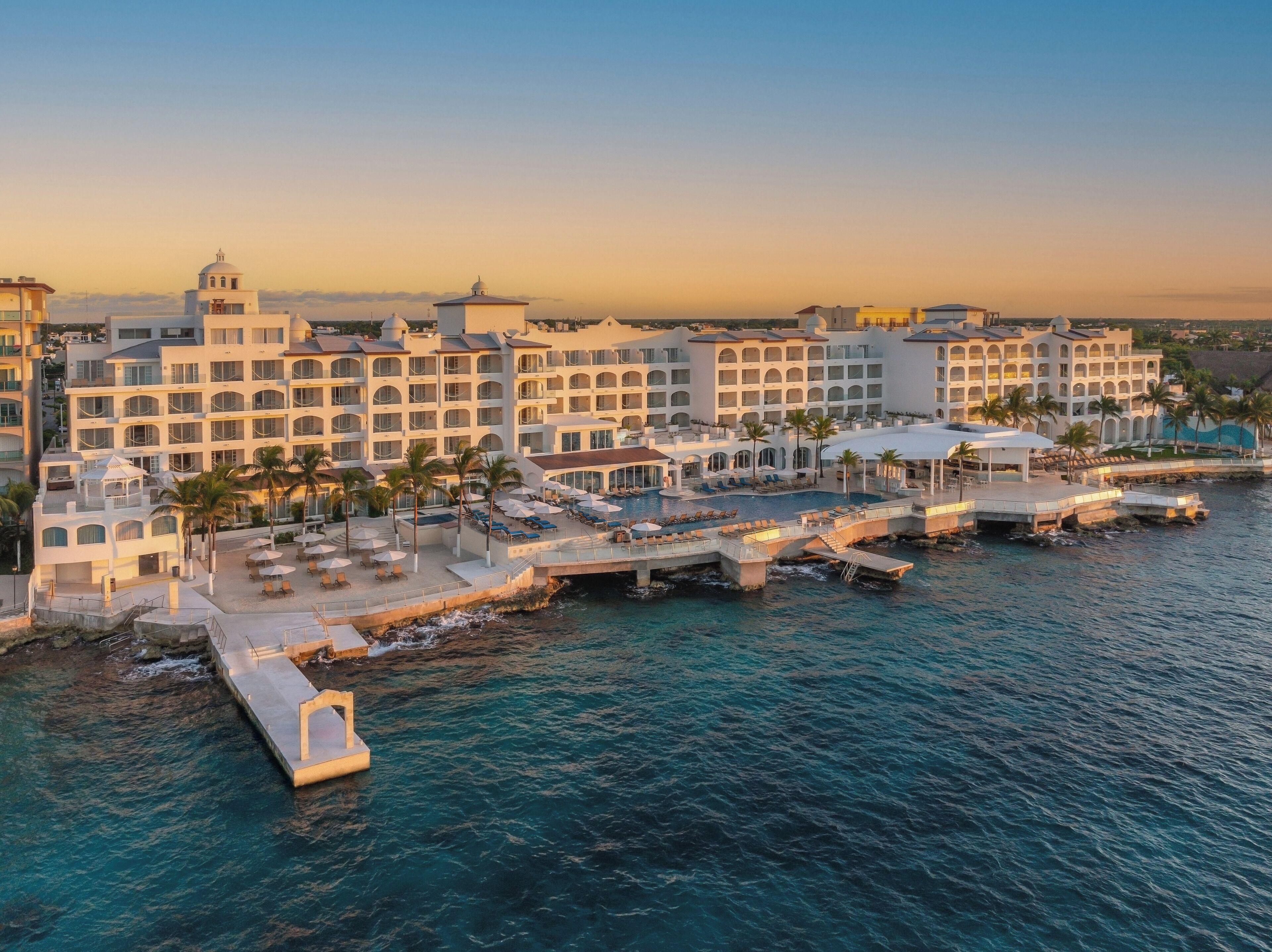 Cozumel Palace buildings, pools and oceanfront at sunset